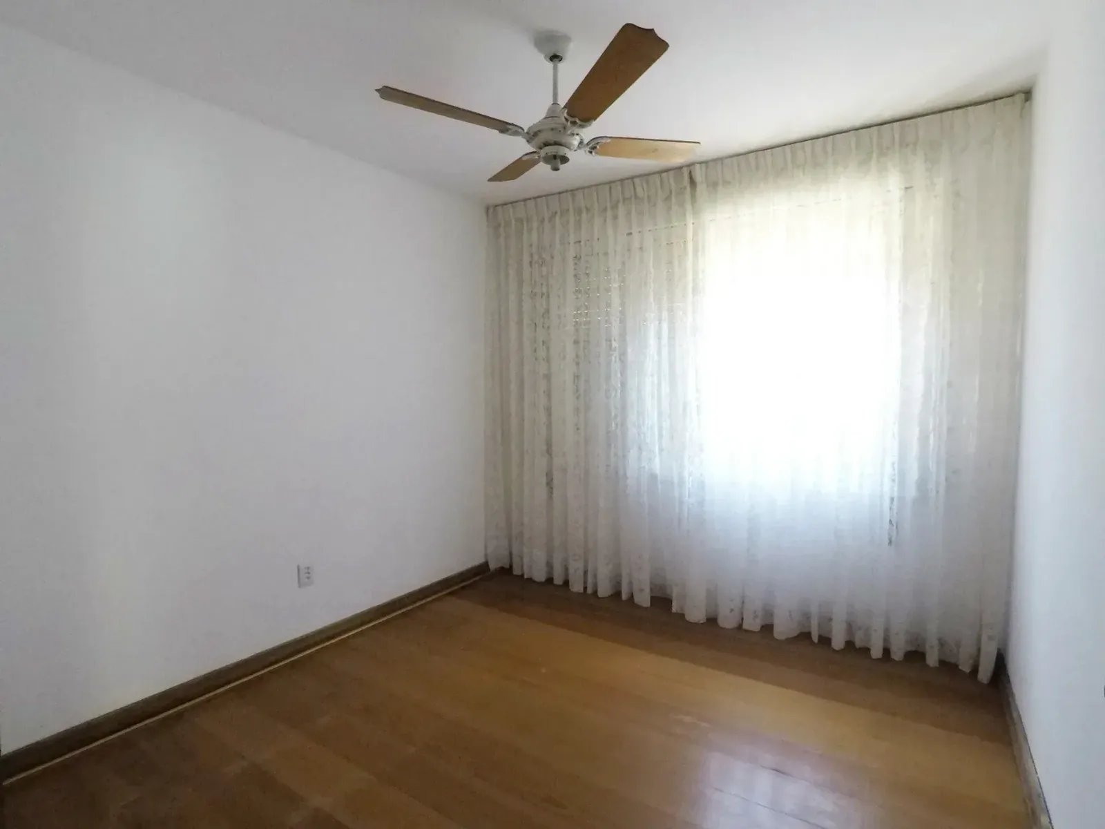 Dormitório com janela ampla e piso de madeira