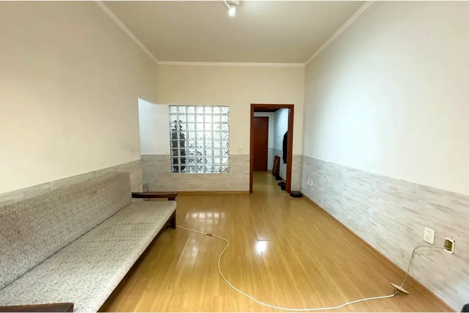 Sala do apartamento térreo em Petrópolis, com piso laminado e tijolos de vidro