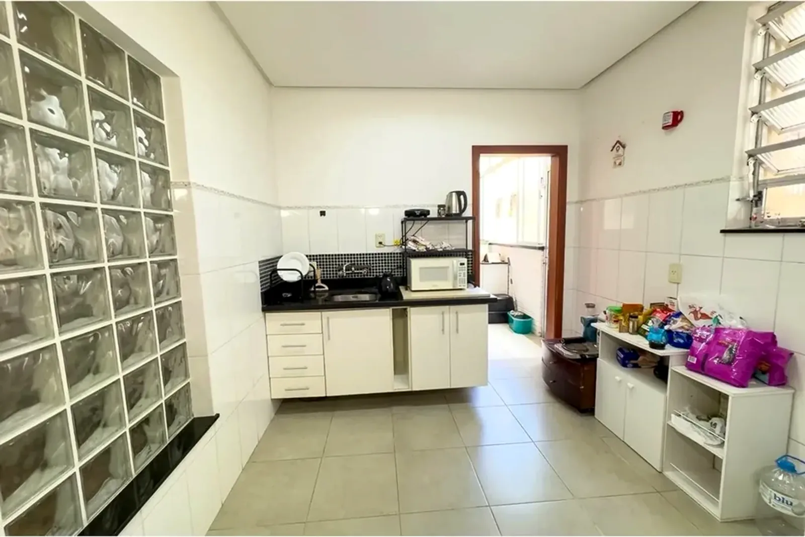 Cozinha com armários brancos e janela