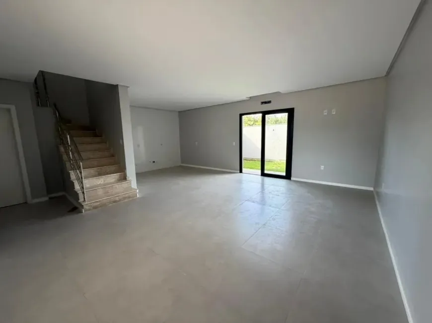 Sala de estar ampla com escada à esquerda e porta de vidro de correr para o quintal ao fundo