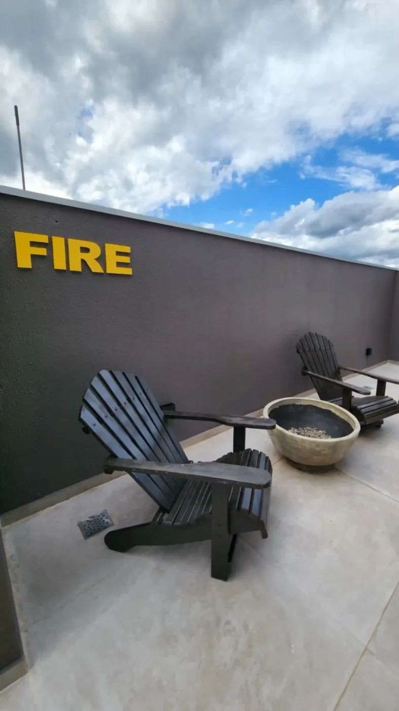 Terraço Fire, com cadeiras de madeira e lareira externa