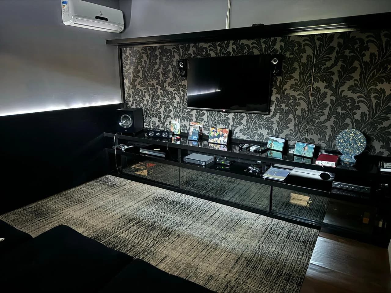 Sala de cinema, com televisão grande e parede revestida.
