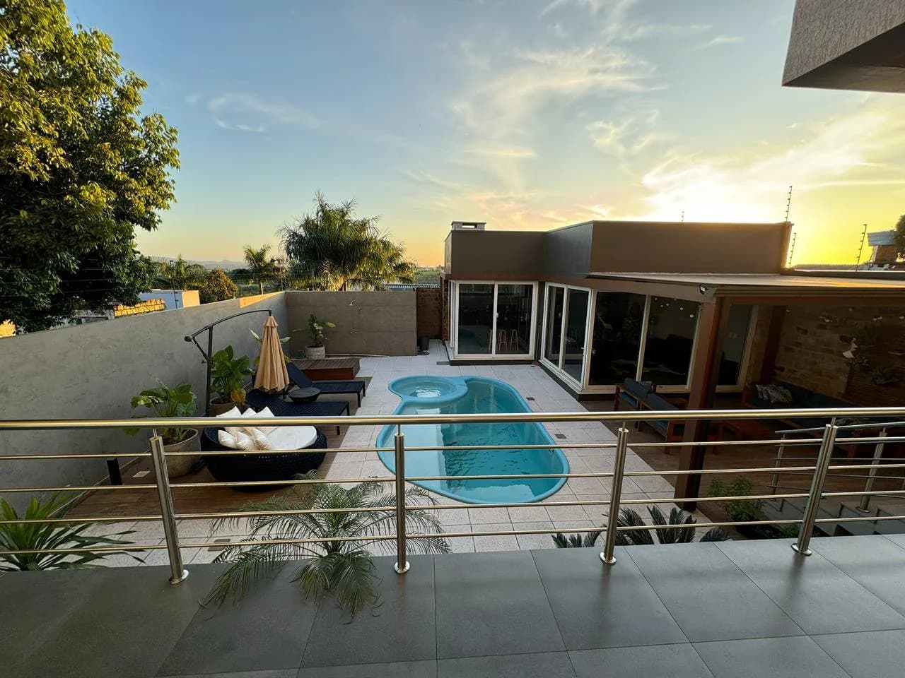 Vista da varanda para a piscina, com o céu no fim da tarde.