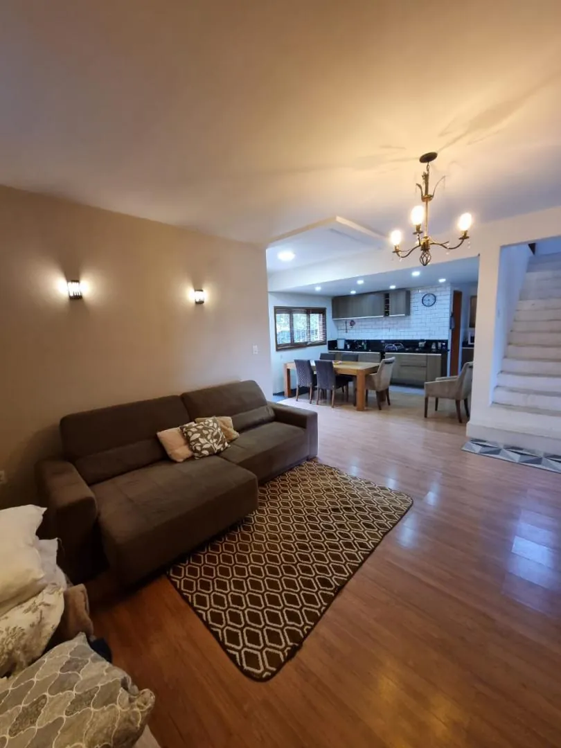 Sala de estar de pé-direito alto, integrada à cozinha ao fundo.