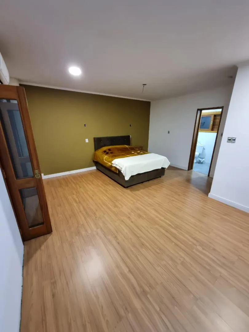 Dormitório com cama de casal e porta de madeira maciça.