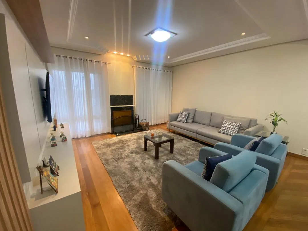 Sala de estar com lareira, sofás azuis e piso de madeira.