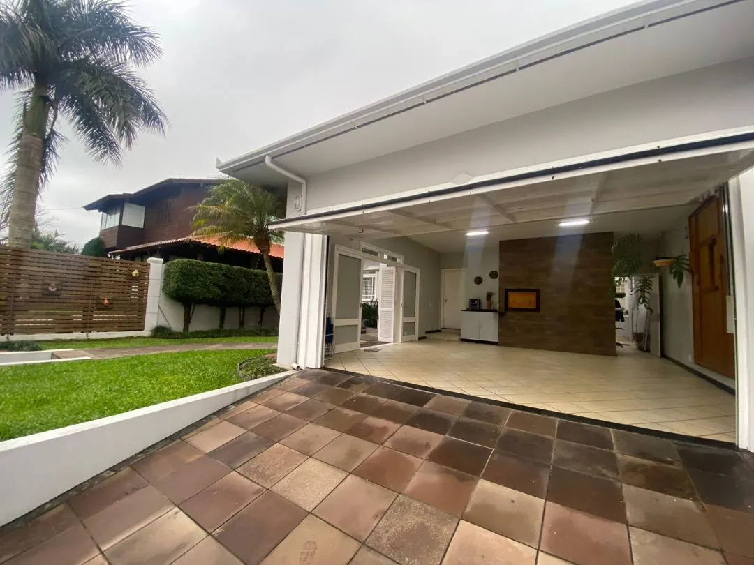 Garagem coberta com piso de lajota, aberta para o jardim.