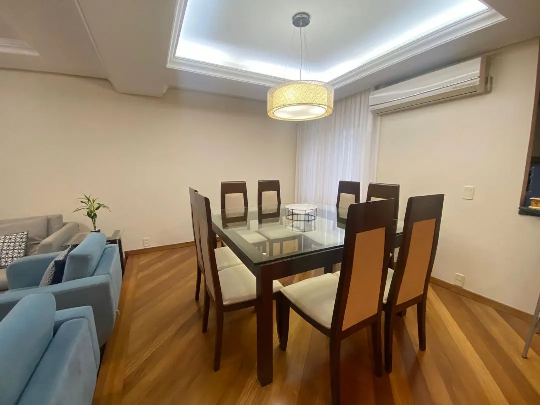 Sala de jantar com mesa de vidro para seis lugares e piso de madeira.