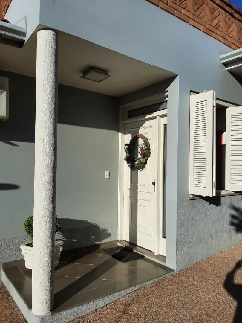 Entrada coberta com colunas e porta branca.