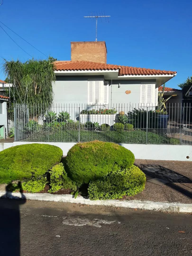 A casa vista da rua, com os arbustos aparados junto ao muro.