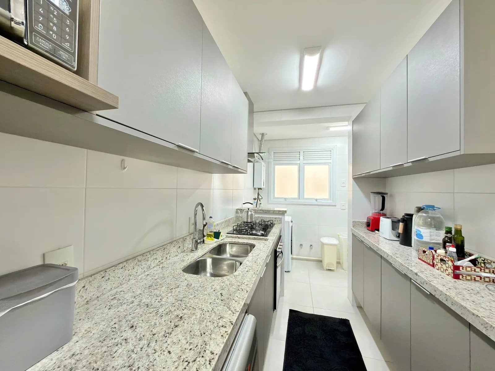 Cozinha do apartamento, com bancada de granito e eletrodomésticos.
