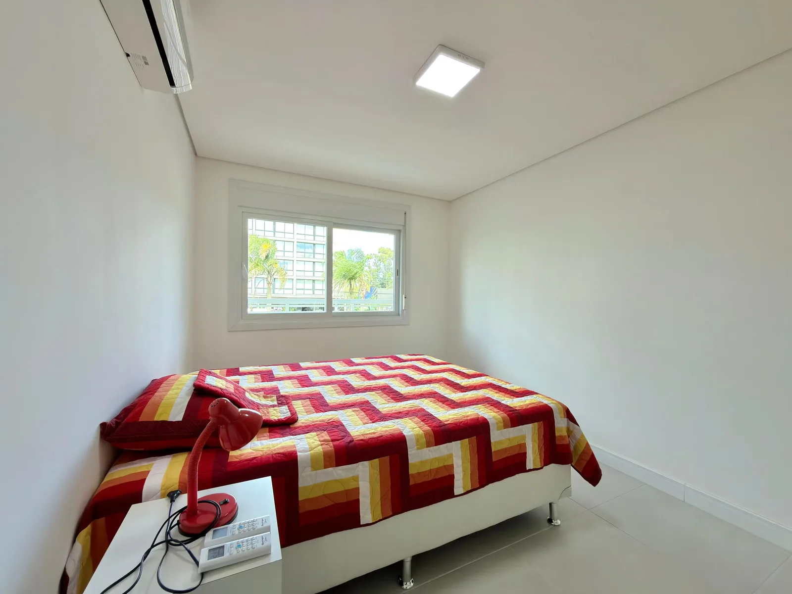 Um dos dormitórios do apartamento, mobiliado, com vista para os prédios vizinhos.