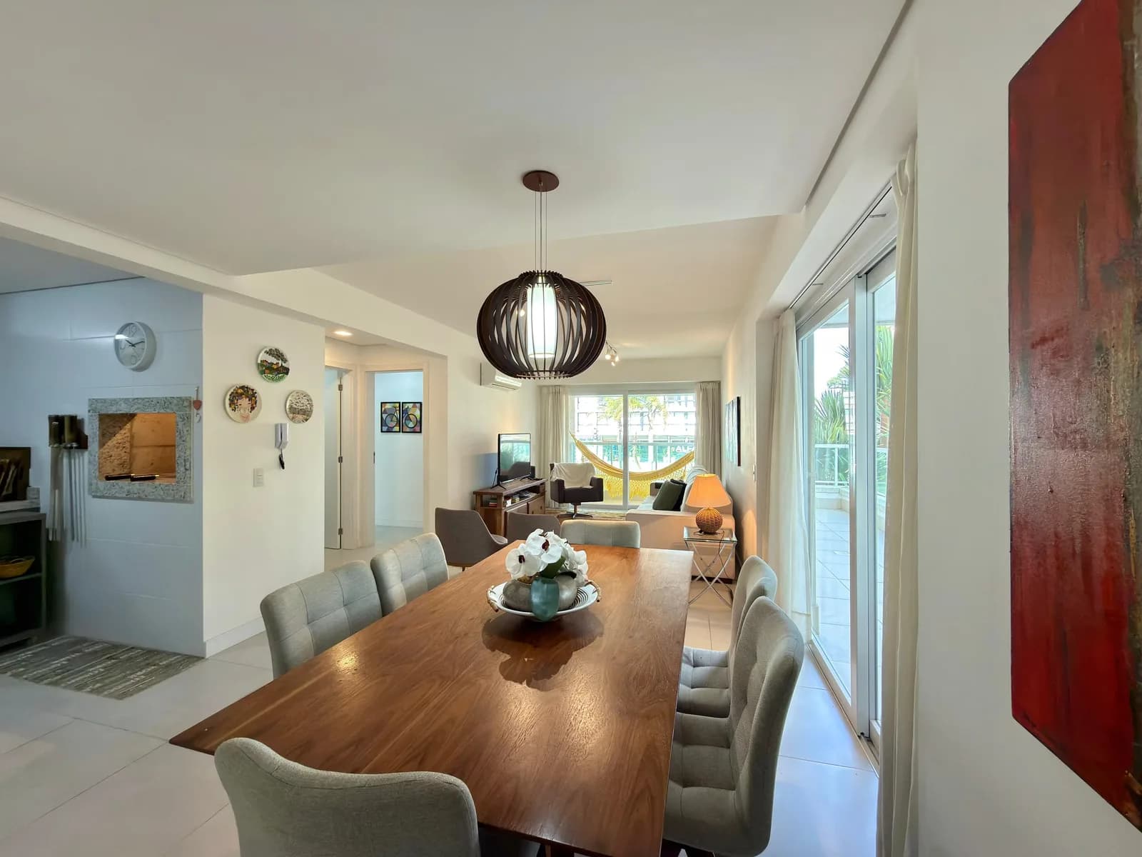 Sala de estar e jantar do apartamento, com a rede na sacada visível ao fundo.