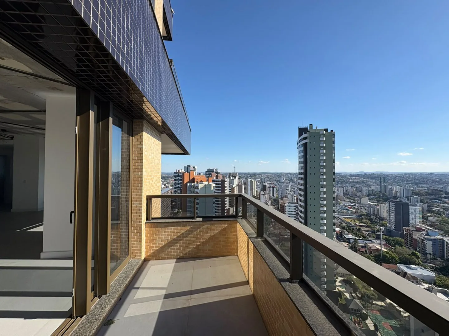 Sacada corrida ao longo da fachada, com portas de vidro e vista da cidade.