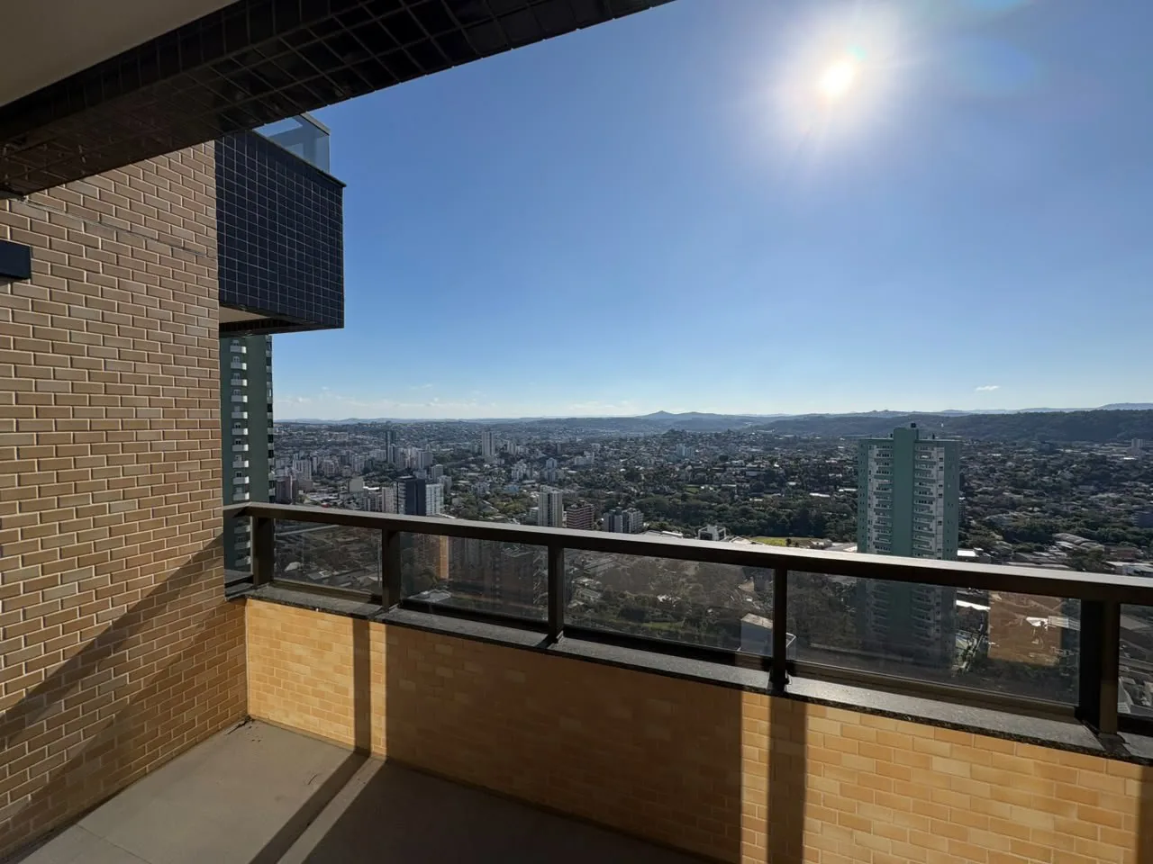 Sacada com parede de tijolo aparente e vista aberta da cidade.