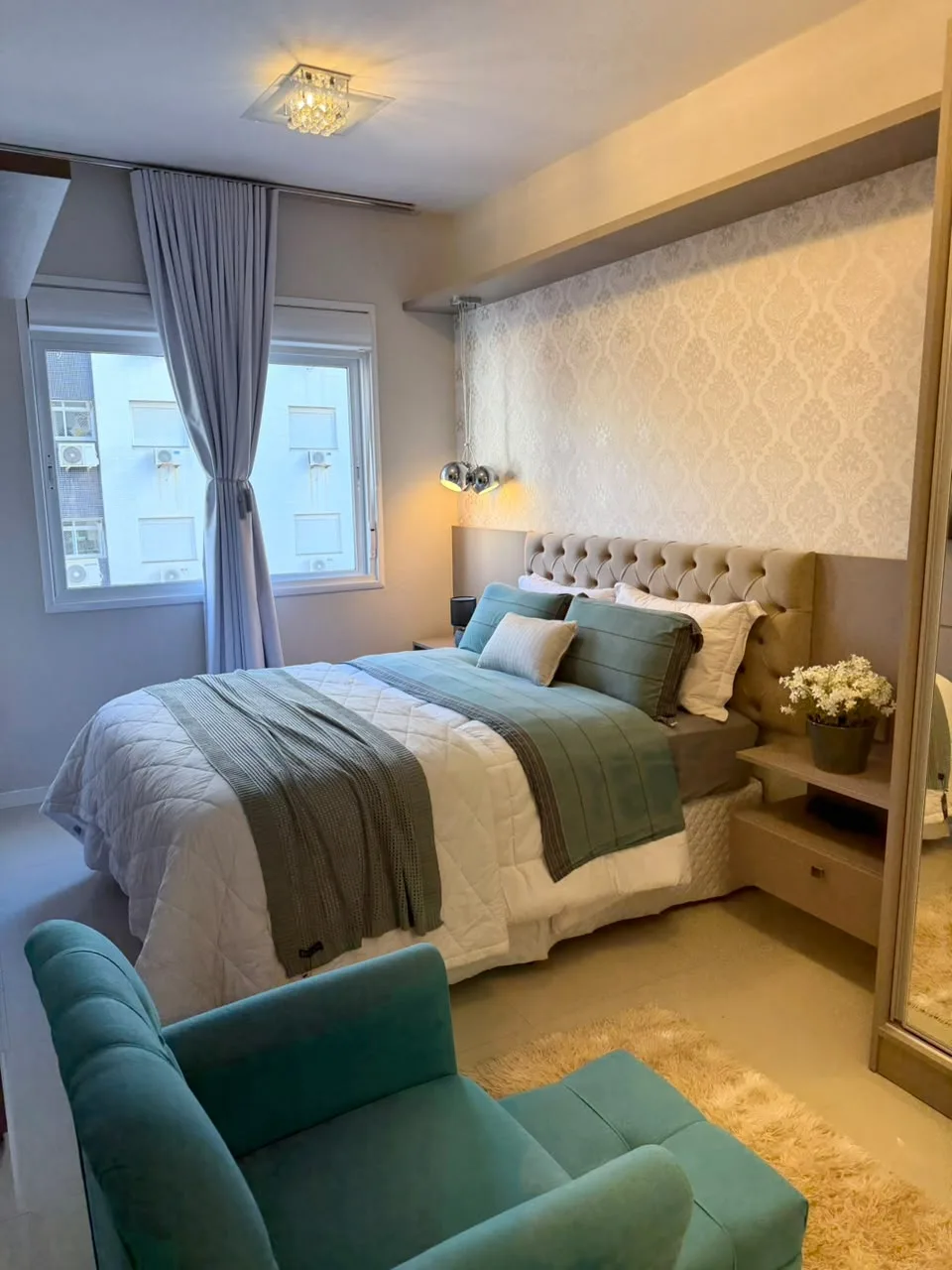 Dormitório com cama de casal e poltrona verde