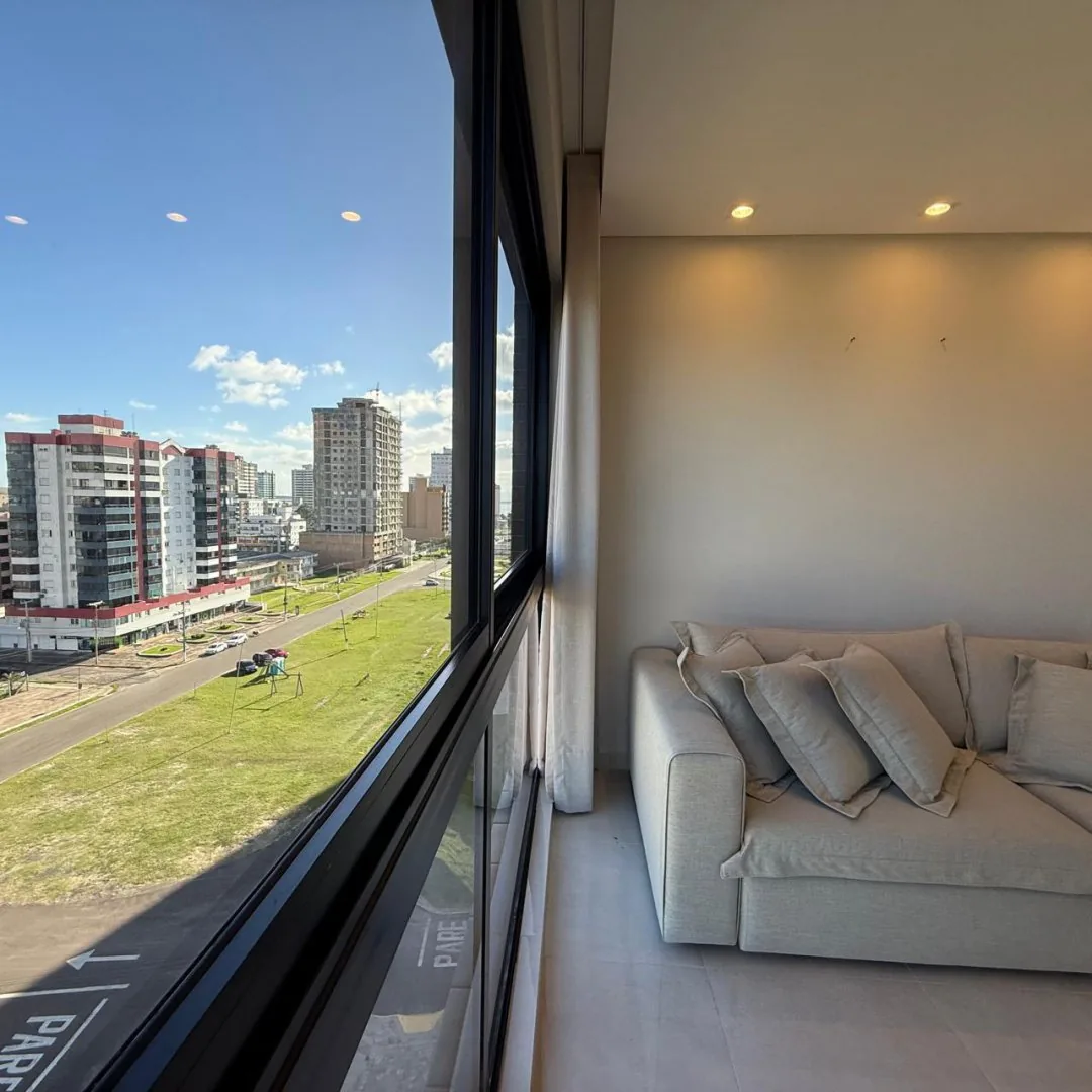 Sala de estar com sofá e vista para a praia.
