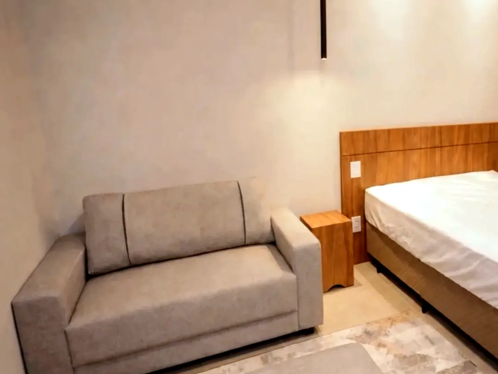 Interior de studio mobiliado, com bancada de trabalho, cama e armário embutido.