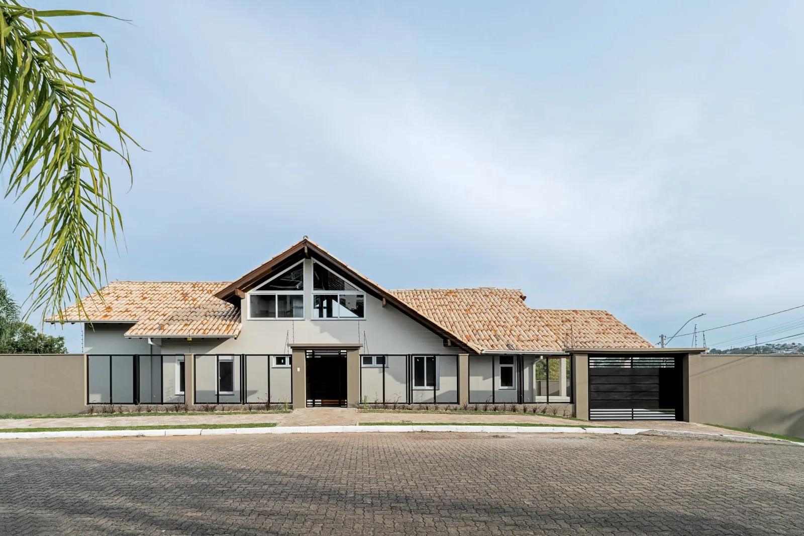 Fachada frontal com garagem coberta e telhado colonial.