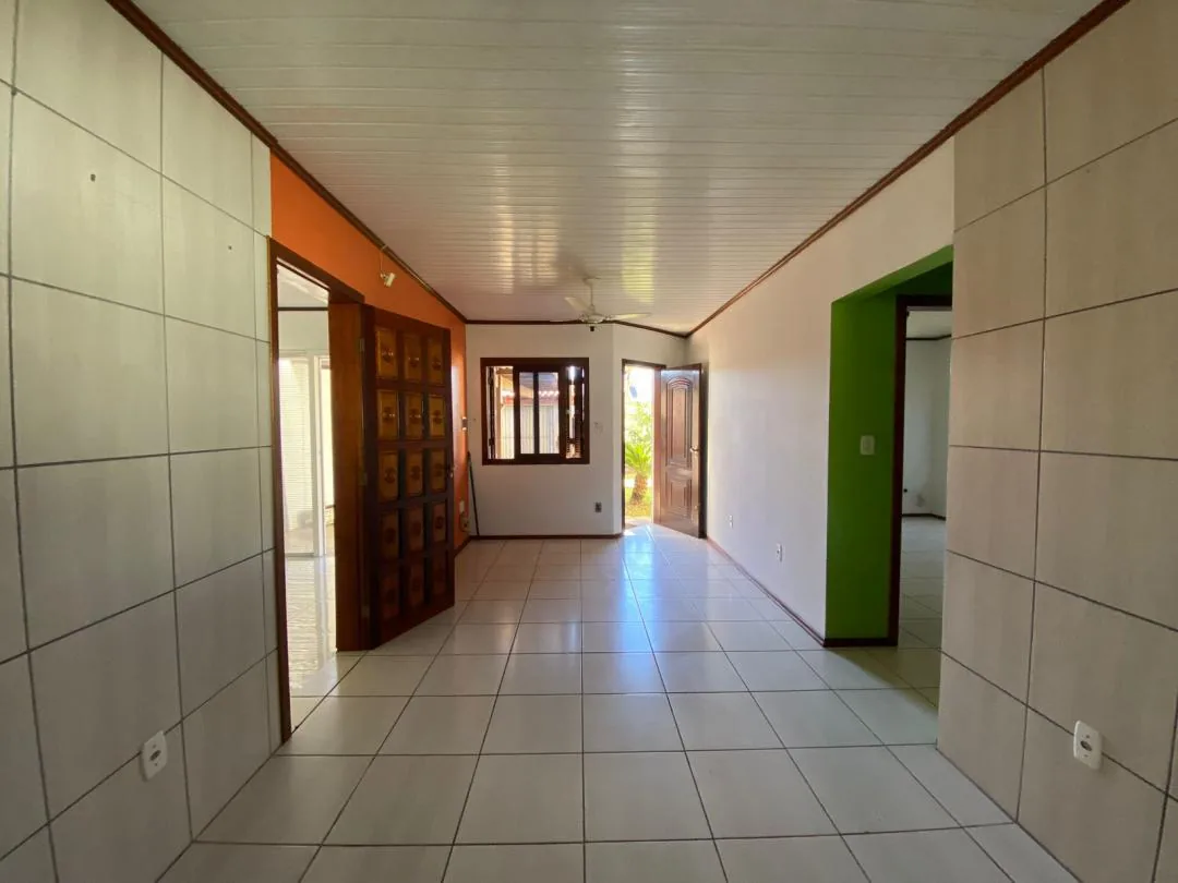 Sala e cozinha integradas vazias com porta de madeira e ventilador.