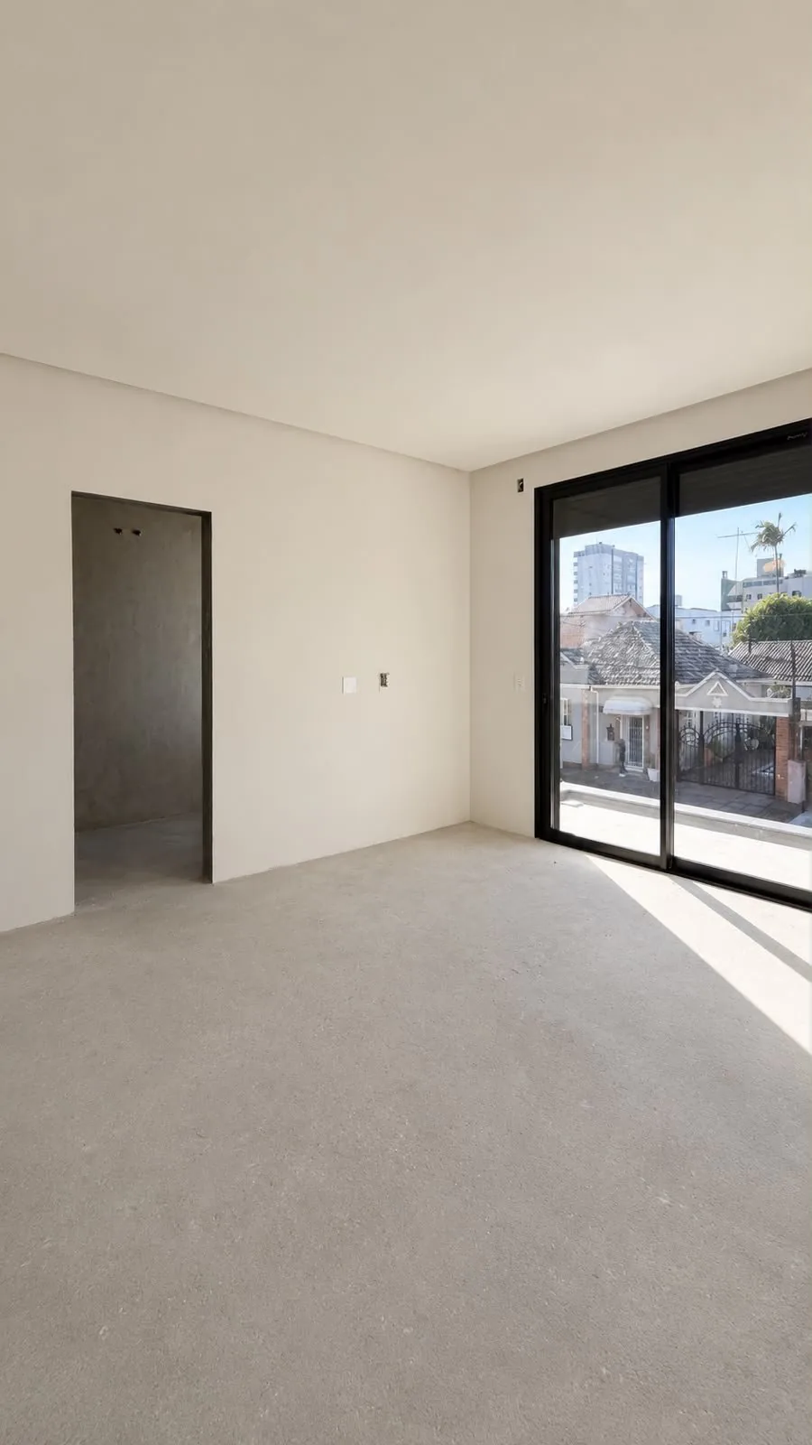 Quarto sem acabamento, com porta de correr para a sacada.