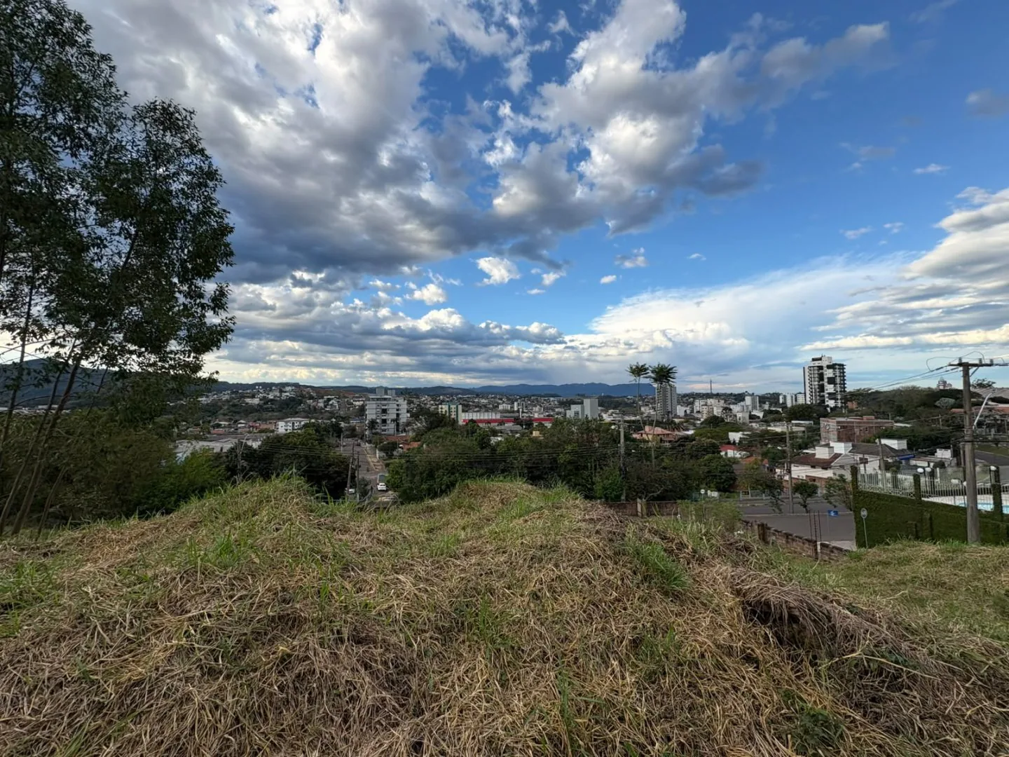 Vista da cidade a partir do terreno, com prédios e morros no horizonte.