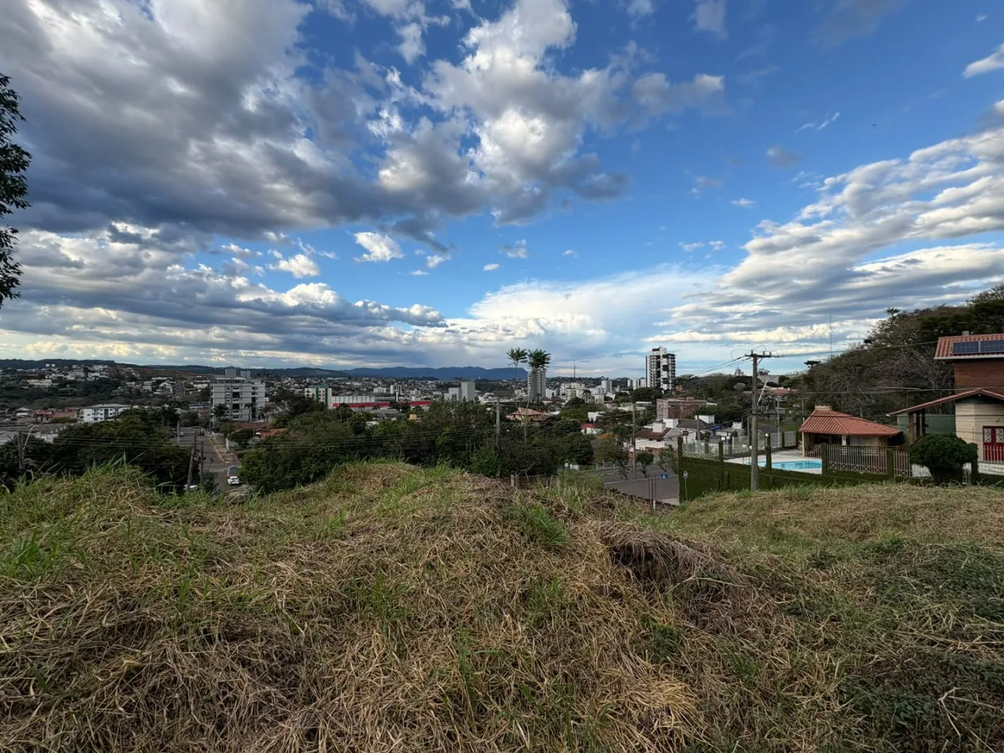 Vista da cidade com prédios, ruas e morros vistos do alto do terreno.