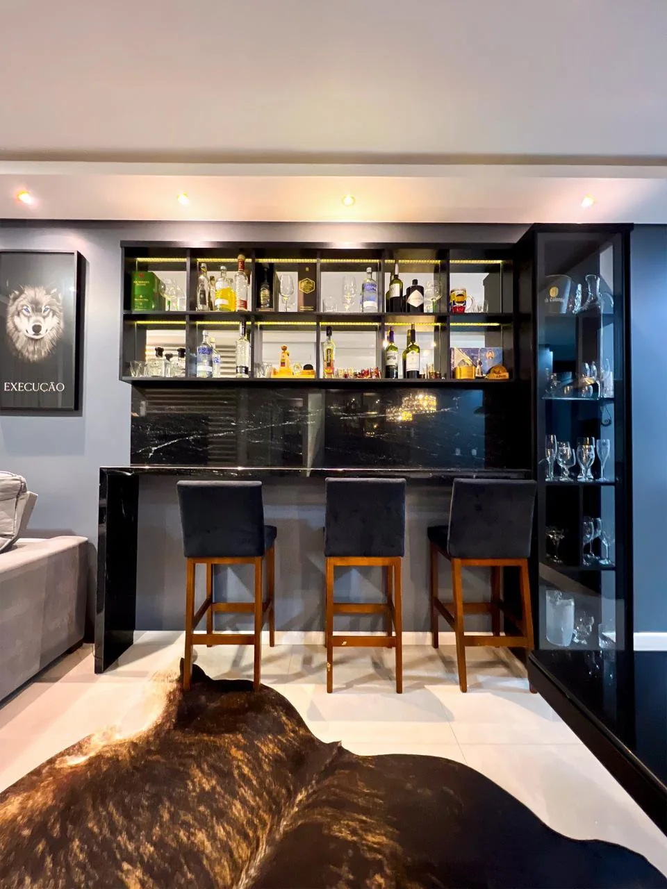 Adega e estante de vidro para bebidas, ao lado do bar da sala.
