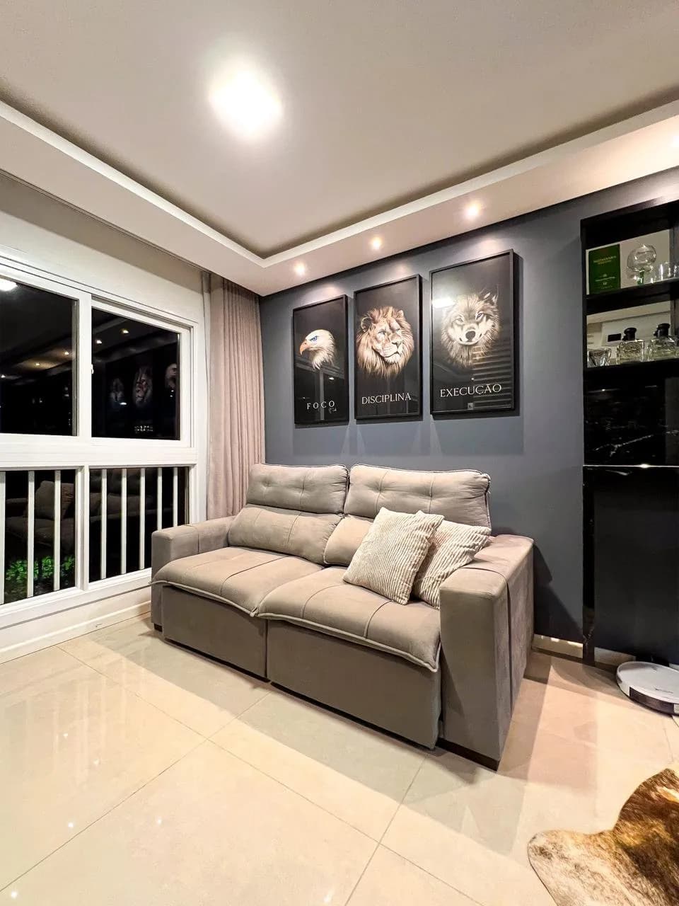 Sala de estar com sofá bege e conjunto de quadros decorativos na parede.
