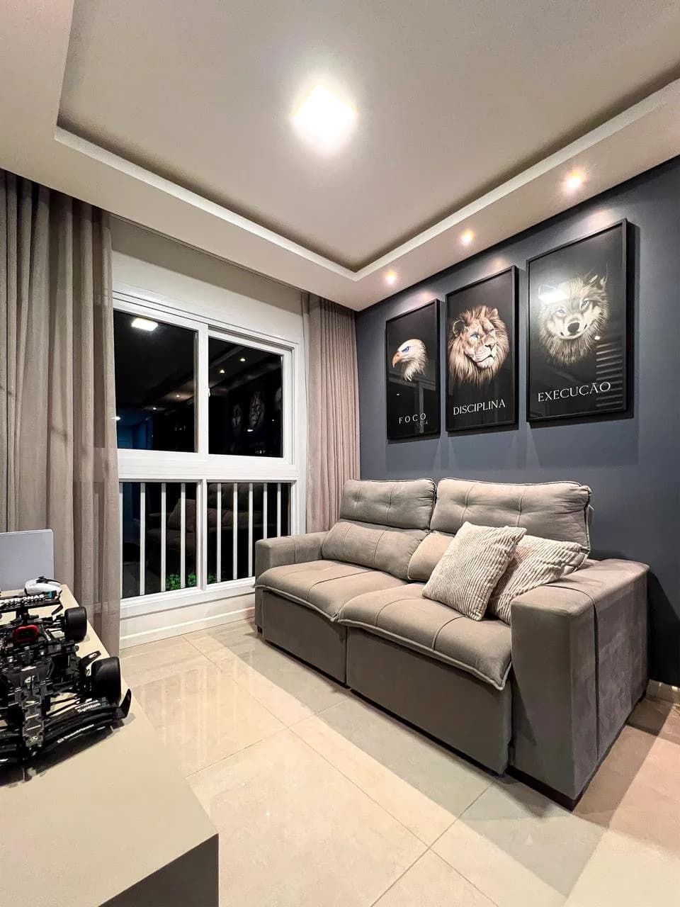 Outro ângulo da sala, com sofá, janela com grade e a sala de jantar ao fundo.