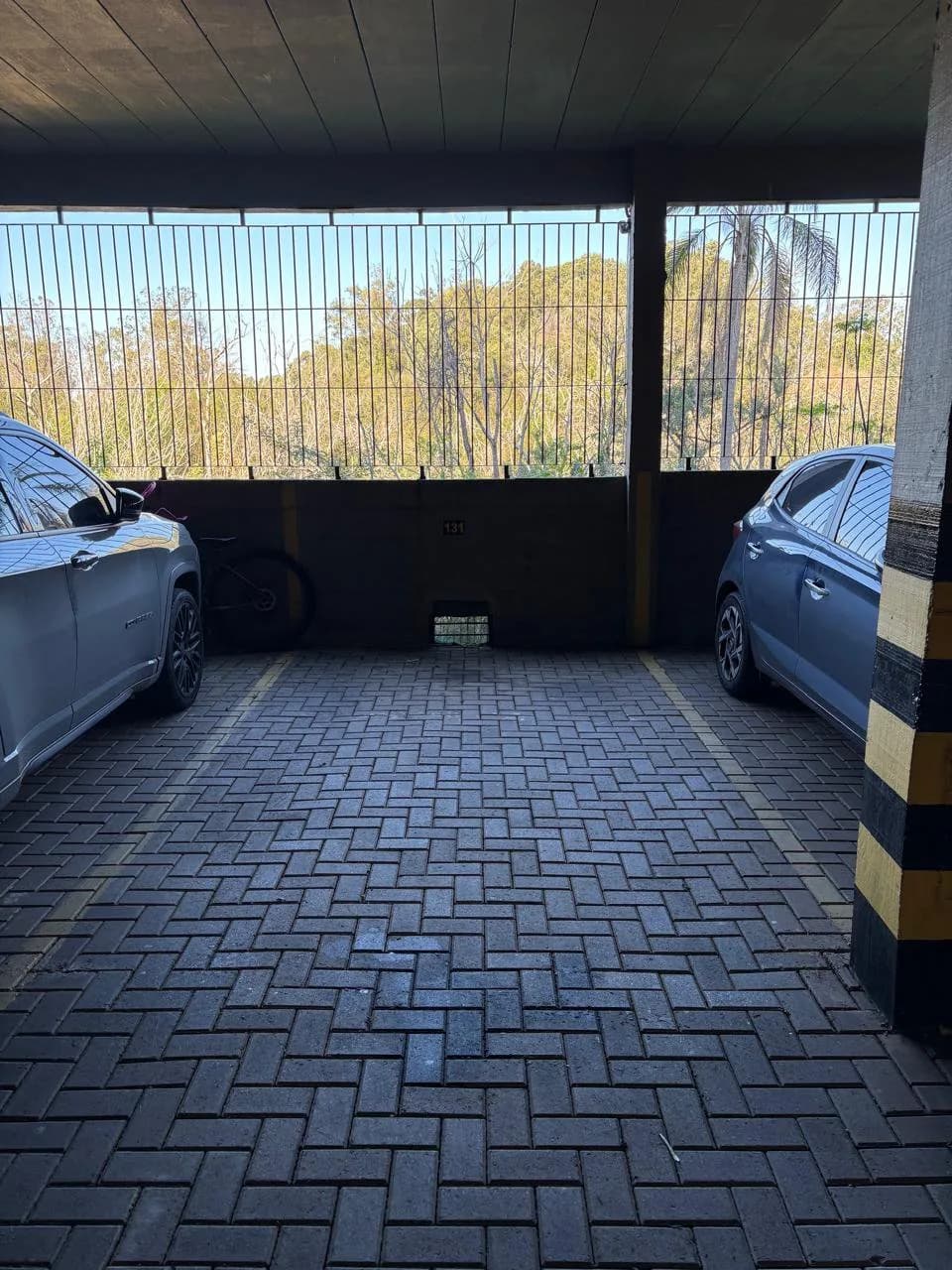 Vaga de garagem coberta do LG67, com dois carros estacionados sob o telhado do prédio.