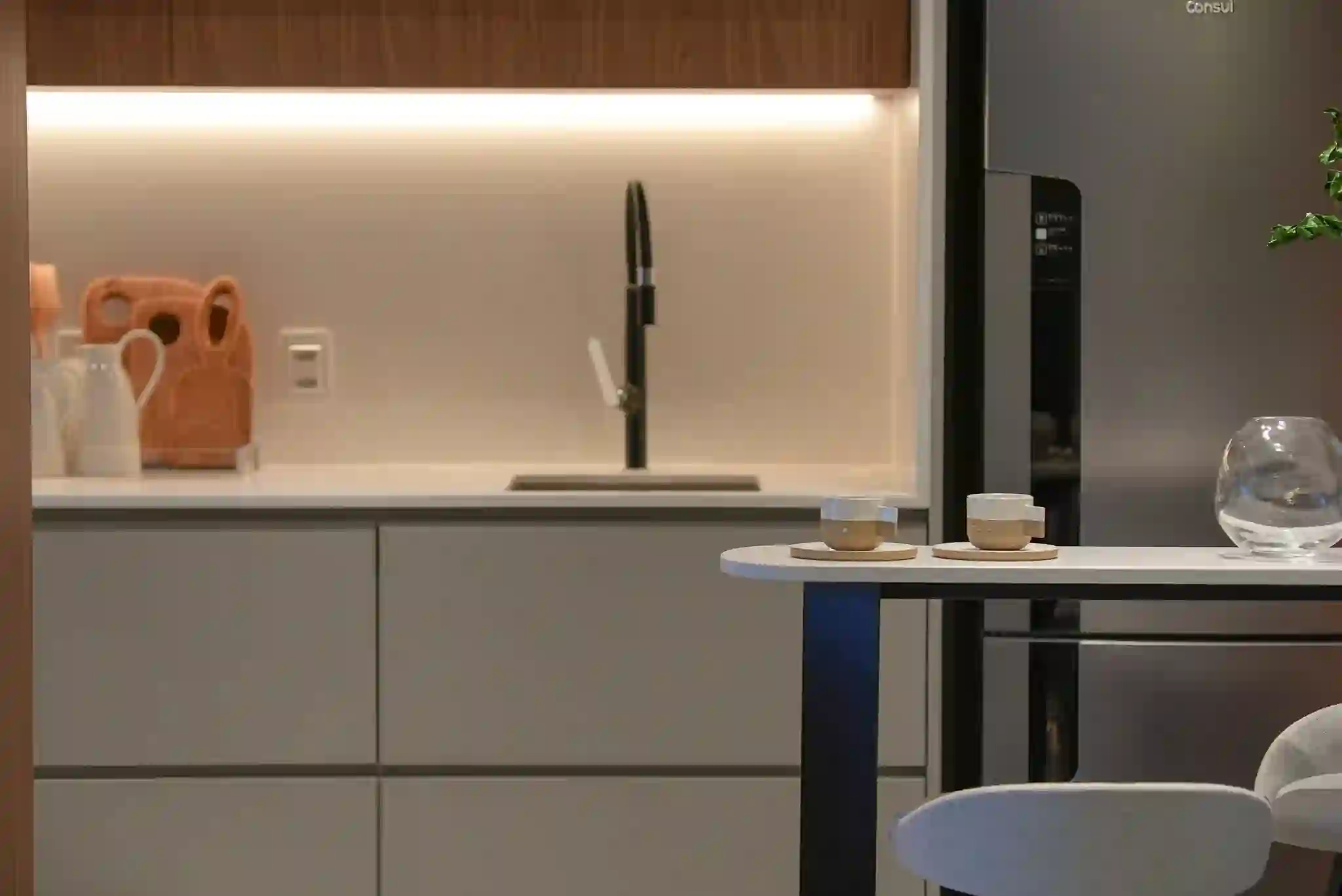 Cozinha do apartamento decorado, com bancada em madeira e iluminação embutida.