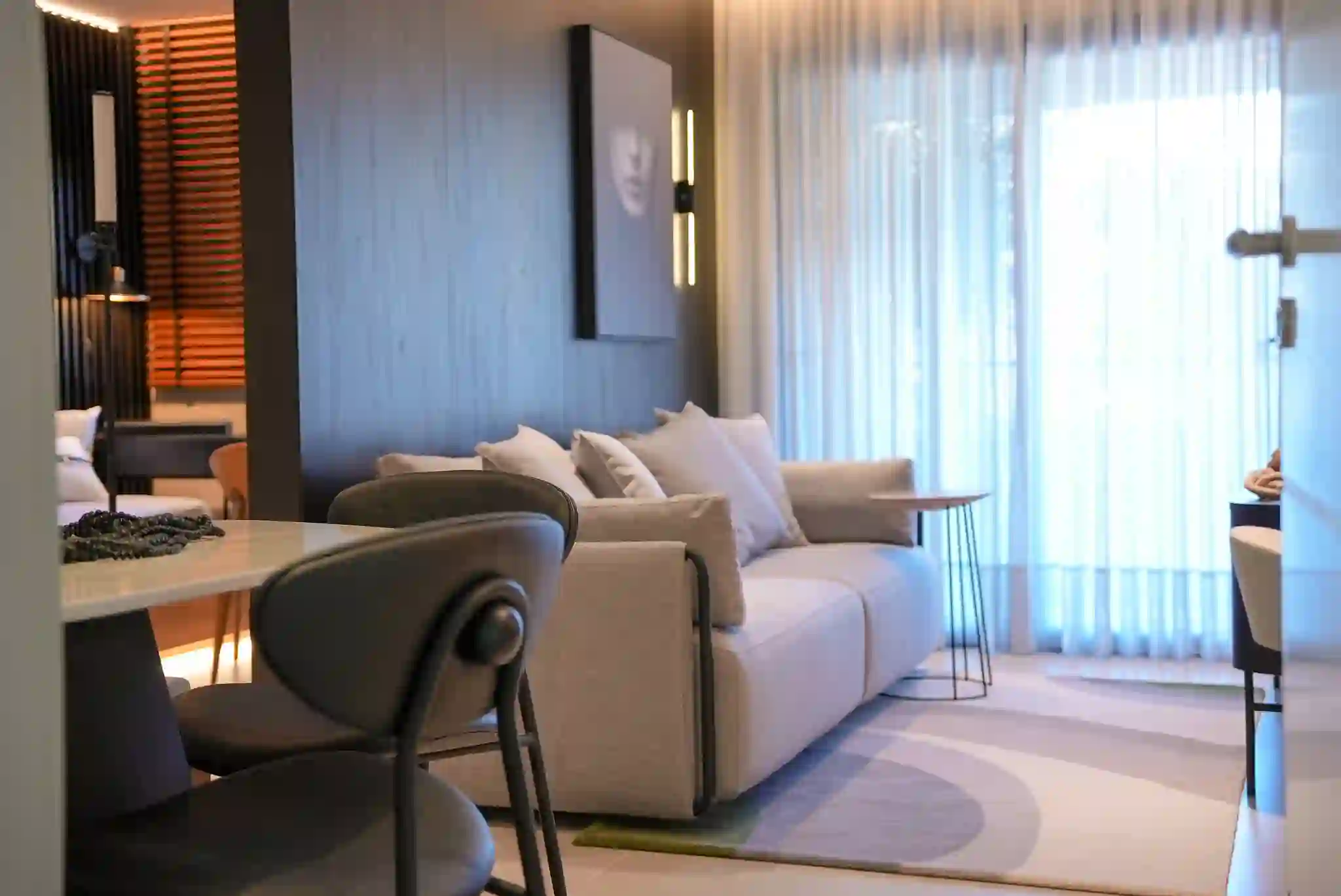 Living do apartamento decorado, com sofá, marcenaria em madeira escura e luz indireta.
