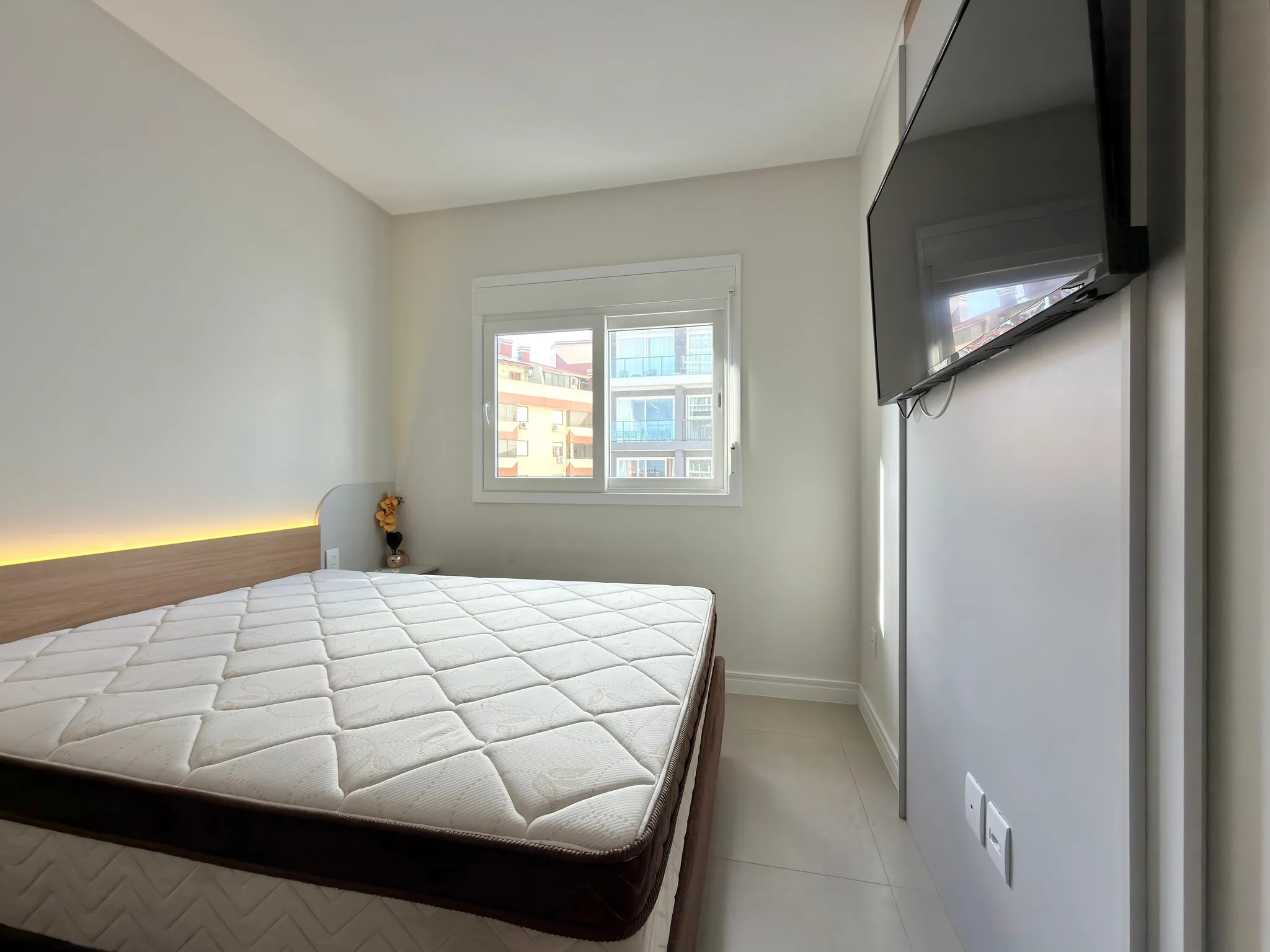 Dormitório da unidade SMART 903, com cama de casal e TV.