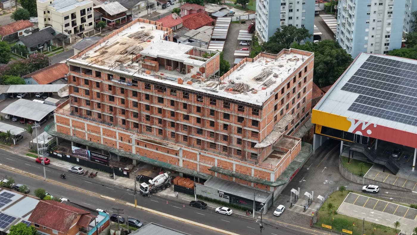 Foto real da obra do Tecno Studios, vista aérea mostrando o entorno e a estrutura já erguida.