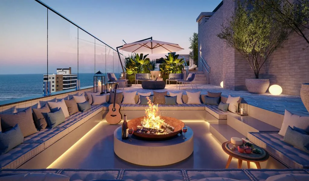 Perspectiva do lounge externo com fireplace no rooftop, no fim da tarde.